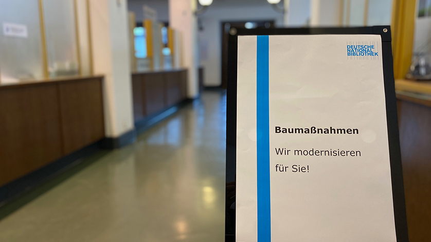 Blick in die menschleere Medienausleihe der Deutschen Nationalbibliothek in Leipzig -  im Gang ein Schild "Baumaßnahmen - wir modernisieren für Sie!